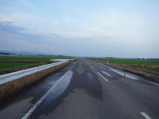 薄曇りの空の下まっすぐに延びる道